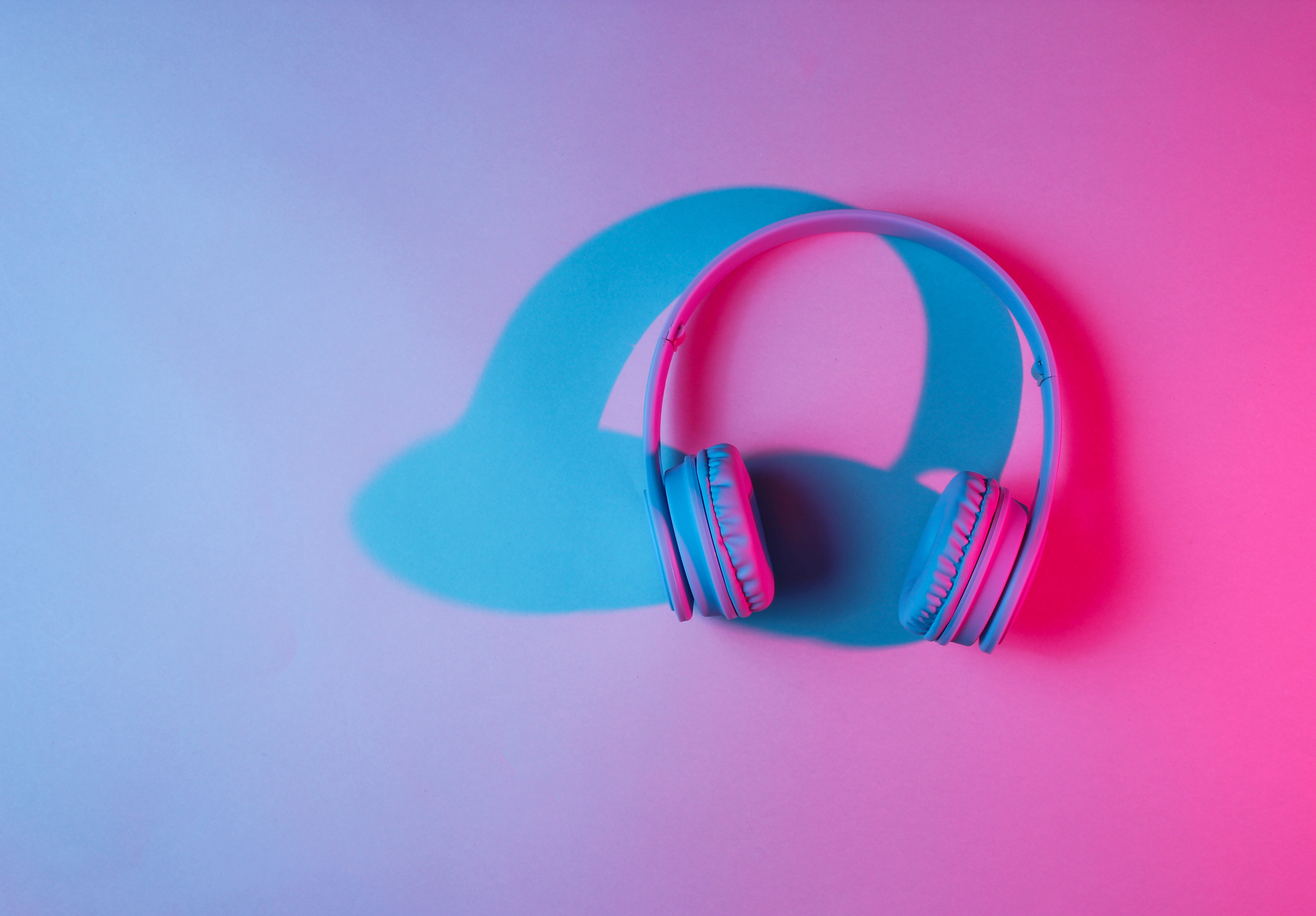 Blue, purple, and pink lights blending together and creating a shadow over a pair of white headphones