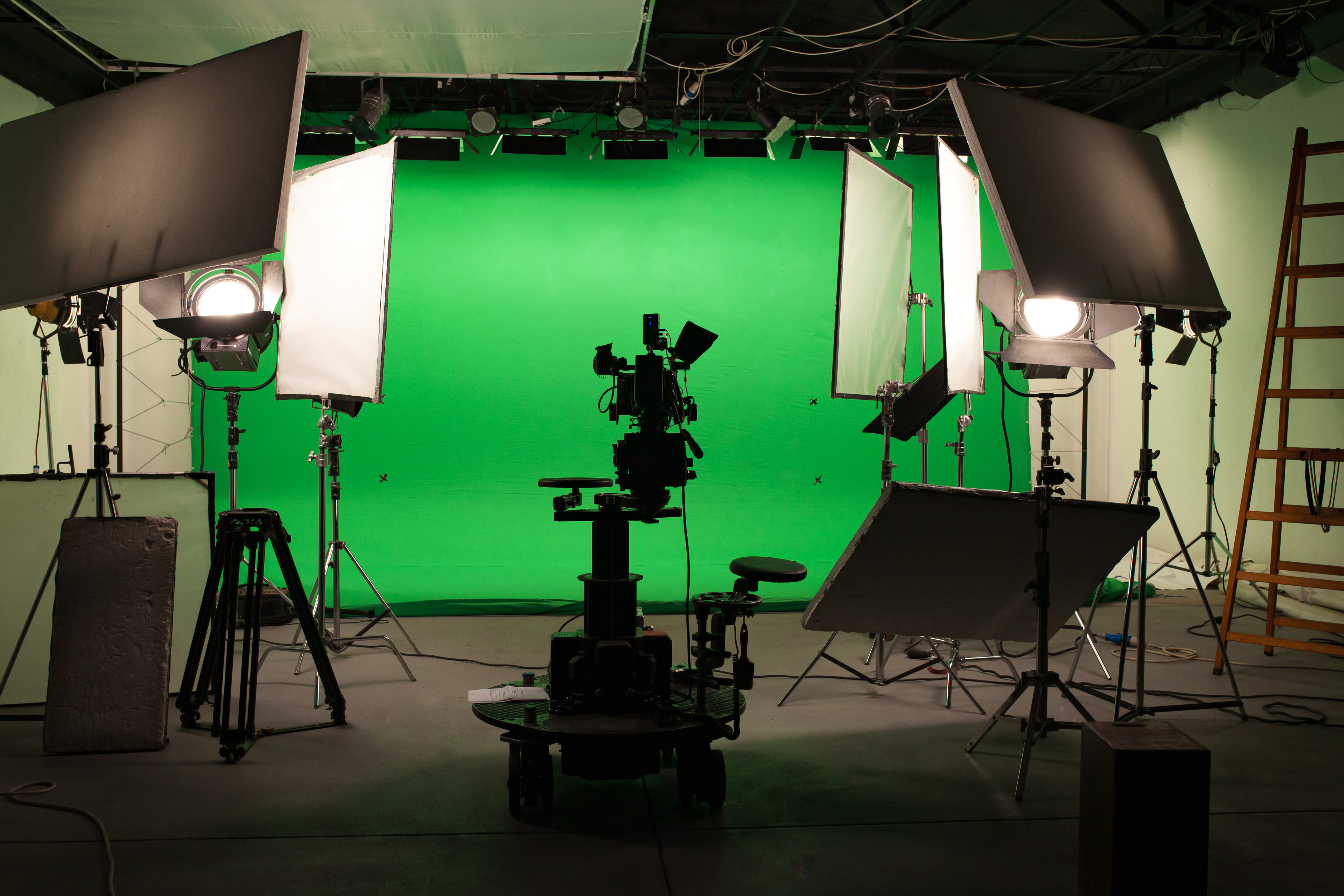 A greenscreen is set up, surrounded by high quality camera equipment and lights